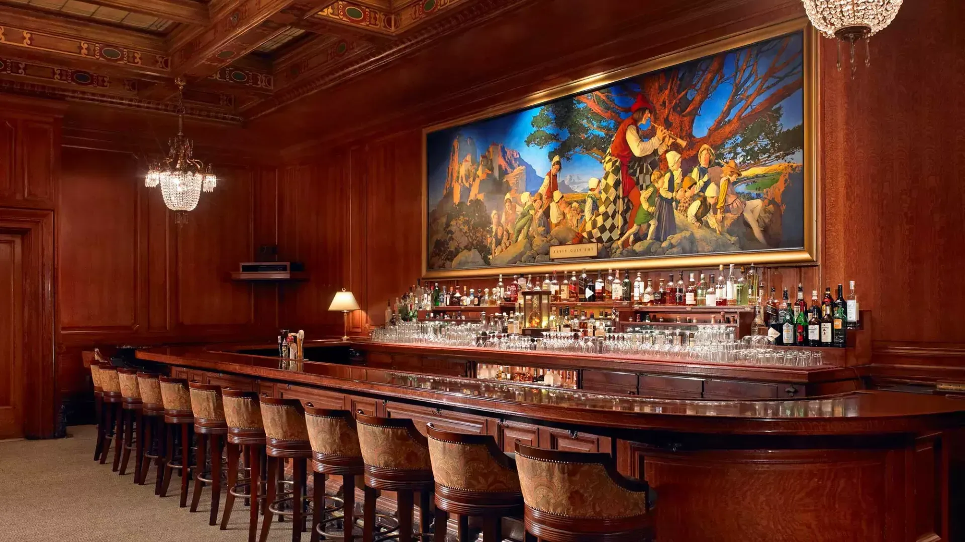 The bar at the Palace Hotel, which features wood-paneled walls and a painting titled The Pied Piper of Hamelin.