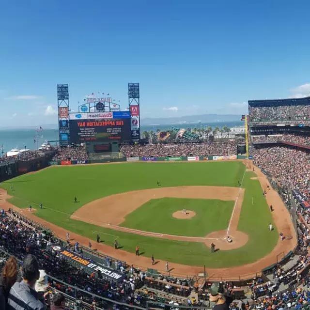 A view of San Francisco's Oracle Park looking out 从 the stands, with the baseball diamond 在 foreground and San Francisco Bay 在 background.